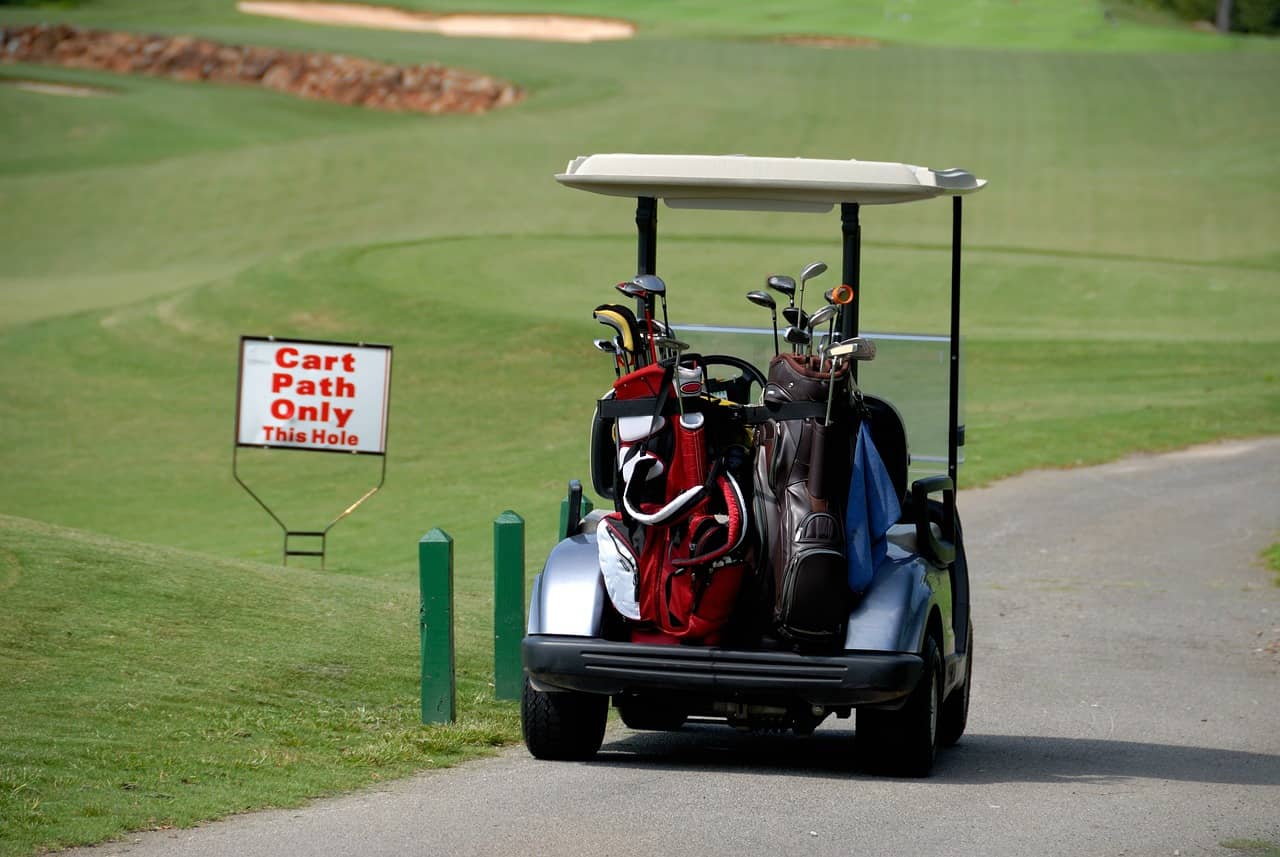 A practical and convenient golf cart parked on the cart path of a golf course, showcasing its utility for golfers.